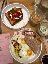 A flat-lay overhead shot of a brunch spread featuring French toast with berries and a savory egg dish with green sauce, accompanied by iced drinks and a menu, promoting brunch spots in Edinburgh.