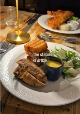 A promotional reel for The Stables at Beamish Hall, featuring a tour of the venue's interior and exterior, followed by a showcase of their new dinner menu, including mains like chicken bearnaise and fish and chips, and desserts like chocolate mousse and affogato.