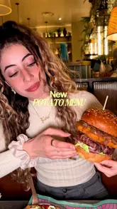 The creator visits Bill's restaurant to review their new 'Potato Menu' collaboration. The video features a tour of the venue, close-ups of various potato-based dishes including a burger, tater tots, and a potato salad, as well as cocktails and a dessert. The creator provides a voiceover review throughout.