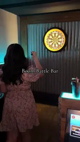 A fast-paced montage showcasing the experience at Boom Battle Bar, featuring clips of customers playing darts and digital games, alongside shots of cocktails and casual bar food like tacos, wings, and fries.