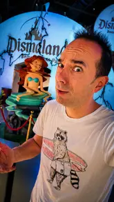 The creator provides a commentary on the 'Dismaland' exhibition by Banksy, contrasting the historical 2015 event with the current 'Banksy Limitless: Reframed' exhibition in London. The video uses a mix of talking-head segments and archival/current footage to explain the satirical nature of the art.