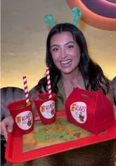 The video features two creators visiting a Shrek-themed cocktail experience called 'Happily Ever After' at Somewhere by Nico. They showcase the themed menu, various creative cocktails, and the entertainment provided by a drag performer acting as the Fairy Godmother. The video captures the fun, immersive atmosphere of the event.