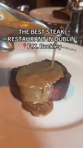 A review of F.X. Buckley in Monkstown, Dublin, featuring a variety of dishes including gambas pil pil, slow-braised pork belly, rib-eye steak, and fillet steak, alongside sides like beef dripping chips and chestnut mushrooms.
