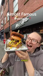 A high-energy, vlog-style review of a 'pickle burger' and various sides at Almost Famous in Manchester. The creator showcases the indulgent, saucy nature of the food, including mac and cheese balls, tater tots, and a cocktail, while maintaining an enthusiastic tone throughout.
