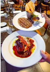 The video features a creator reviewing an early evening set menu at The Whitehall restaurant in Leeds. It showcases various courses including French onion soup, scallops, ribeye steak, chicken, and desserts, alongside wine, while highlighting the value of the deal.