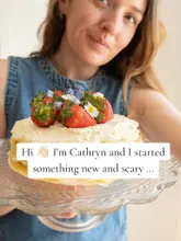 A creator introduces her new project, 'Recipe Club,' by holding up a homemade crepe cake decorated with fresh strawberries and flowers, creating an inviting and personal introduction.
