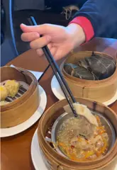 A video showcasing a variety of dim sum dishes at a Chinese restaurant. The creator uses chopsticks to pick up and display each item, including siu mai, har gow, xiao long bao, and cheung fun, often dipping them in sauce. The video focuses entirely on the food, with no shots of the venue interior or atmosphere.