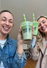 The video follows a creator taking her friend to try matcha for the first time. They visit a coffee shop to purchase the drinks and then proceed to a studio space to taste-test them, discussing their preferences and reactions.