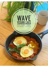A vlog-style review of a vegan cafe in Hackney, featuring a variety of menu items including coffee, sandwiches, shakshuka, pastries, and a cookie.