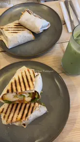 A short, music-led video showcasing the interior, exterior, and menu items of Leaf and Bean cafe in Washington. The video features shots of the cafe's seating, coffee machine, and food offerings, including a wrap and a matcha latte.