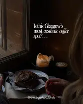 A moody, atmospheric close-up shot of a cinnamon bun and a coffee cup on a table, illuminated by a single candle. The image effectively captures a cozy, aesthetic coffee shop environment, emphasizing the intimate and inviting nature of the venue.