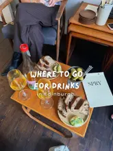 A high-angle, lifestyle-focused shot of a wine bar table featuring glasses of wine, a bowl of olives, and slices of sourdough bread, with a menu visible. The image captures a relaxed, sophisticated atmosphere suitable for a wine bar setting.