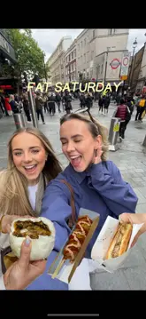 Two creators spend a 'Fat Saturday' exploring various street food vendors and a supermarket in London's Chinatown. They visit five different spots, trying items like Chinese-inspired burgers, steamed buns, bubble tea, corn dogs, and Asian desserts, providing quick, enthusiastic reviews of each.
