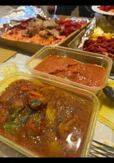 The video features a creator reviewing a large 'munch box' from an Indian takeaway called Kebabwalla. It includes shots of the shop exterior, the kitchen staff cooking the food, and the creator tasting the various components of the box, including tandoori meats, fries, and curry.