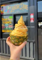 A short, rhythmic video showcasing the preparation and serving of soft-serve ice cream inside hollowed-out fresh fruits like pineapple, mango, watermelon, and dragonfruit at Lahori Lane in Manchester.