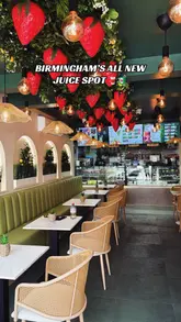 A bright, well-composed interior shot of a new juice bar in Birmingham, featuring eye-catching strawberry-themed ceiling decor and a clean, modern seating area.