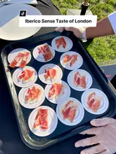 A vlog-style reel capturing a visit to the Taste of London food festival, focusing on the Ibérico Sense stand. The creator showcases various food items, including dumplings and chocolate, before highlighting the Ibérico ham, explaining its origin, and showing a live slicing demonstration.