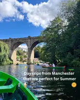 A scenic, first-person perspective shot taken from a boat on a river, featuring a large stone viaduct in the background. The image captures a quintessential summer day trip vibe, using natural lighting and a clear, inviting composition to showcase the location.