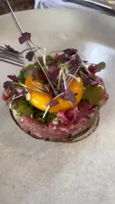 A high-quality, polished montage showcasing a selection of dishes at The London Carriage Works, including steak tartare, fresh bread, fish, duck, and a dessert, accompanied by a voiceover review.