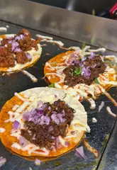 A short, punchy review of Taco Boom in Brixton, focusing on their £3 tacos, quesadillas, and loaded fries. The video features close-up shots of food preparation, cheese pulls, and sauce application, accompanied by a voiceover review.