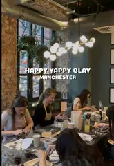 A montage video showcasing a group of people participating in a relaxed, wholesome air-dry clay workshop in a bar/cafe setting. The video highlights the social nature of the activity, showing participants chatting, drinking, and crafting pinch pots.