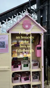A short vlog showcasing an 'honesty cake box' located near the canal in Edinburgh, featuring a variety of homemade cakes and treats available for purchase via cash or QR code.