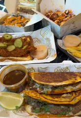 A promotional video showcasing a new menu at Bollos, featuring close-ups of various indulgent dishes like loaded fries, tacos, and burgers, alongside shots of the menu and venue interior.