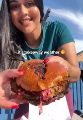 A creator reviews a takeaway order from Kongz in Glasgow, showcasing a variety of indulgent items including smash burgers, loaded fries, and mozzarella sticks while enjoying the sunny weather outside.