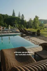 A high-quality, serene photograph of an outdoor spa pool and lounge area at The Coniston Country Estate in the Yorkshire Dales. The image captures the morning light, highlighting the tranquil setting with a view of the surrounding landscape.