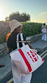 A group of friends enjoys a beach day in Dublin, featuring a swim at Seapoint Beach and a KFC picnic with chicken tenders, chips, and a variety of dips, all while wearing branded KFC robes.