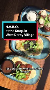A review of 'The Snug' in West Derby Village, Liverpool, by the 'Scouse Ghetto Gourmet' as part of his 'Help A Business Out' (HABO) series. The video showcases the venue's interior and several dishes, including Stornoway black pudding with scallops, lamb croquettes, and a sirloin steak.