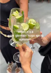 A promotional video showcasing a Saint Germain Hugo Spritz pop-up event at Café en Seine. The video features quick cuts of the venue, the preparation of the cocktails, and groups of people enjoying the drinks in a stylish, outdoor-style setting.