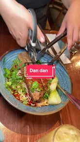 The creator visits Dan Dan, a Chinese restaurant in London, providing a review of their experience. The video features close-ups of various dishes including beef ribs noodles, spring rolls, dim sum, squid, soup, and cucumber salad, alongside shots of the restaurant's interior and the creator enjoying the food.