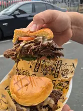 A candid, handheld video review of a brisket burger and fries from Unit Burger in Sheffield. The creator provides a direct, enthusiastic assessment of the food's taste and texture while standing outside the venue.