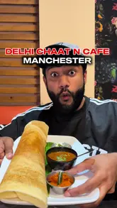 A creator reviews Delhi Chaat N Cafe in Manchester, showcasing a variety of Indian street food dishes including dosa, chicken 65, lamb chops, and chicken tikka masala. The video features the creator tasting the food, showing the menu, and providing a brief tour of the venue's interior.
