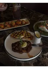 A short montage video showcasing the interior and menu items of Decorum restaurant in Birmingham, featuring cocktails, steak, bao buns, and crispy cauliflower.