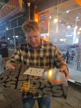 A creator reviews a meal from German Doner Kebab in Cardiff, showcasing the packaging, various sauces, a spring roll, and a mixed doner and chicken kebab. The video is shot in a vlog style outside the venue at night, with the creator providing enthusiastic commentary on the food quality.