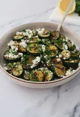 A concise, top-down recipe tutorial demonstrating how to prepare grilled courgettes with feta, lemon, and parsley.