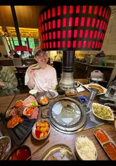 Two creators visit Ban di bul in Manchester for their first Korean BBQ experience, documenting the process of grilling meat and assembling lettuce wraps. They highlight the tasting platter for two, various sides like seafood pancake and kimchi, and the helpfulness of the staff in guiding beginners.