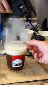 A short, enthusiastic review of Tasse Coffee in Glasgow, focusing on their unique, visually creative coffee specials. The creator visits the shop, shows the menu, observes the preparation process involving smoke and bubble effects, and tastes the drinks, sharing positive reactions.