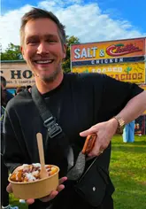 A vlog-style video documenting a visit to the Foodies Festival at Rouken Glen Park, featuring the creators walking around, interacting with stallholders and attendees, and sampling various food and drink items.