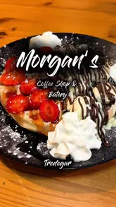 A vlog-style review of Morgan's Coffee Shop and Eatery in Tredegar, featuring two creators trying a variety of dishes including a Sunday roast, smashed burger, chicken tenders, waffles, and milkshakes.