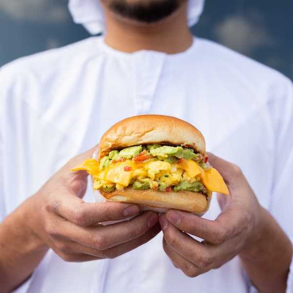 An influencer holds out a burger in their hands